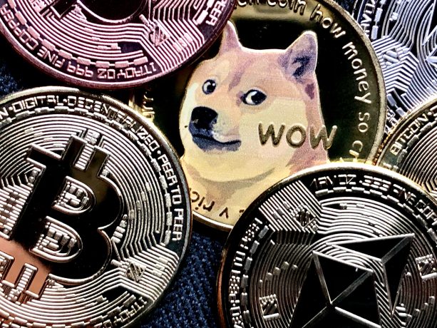 Physische Münzen, die Bitcoin, Ethereum und Dogecoin repräsentieren – angeführt von einem prominenten Dogecoin mit dem Shiba Inu-Hund und dem Wort WOW – fangen das Aussehen eines automatisch gespeicherten Entwurfs digitaler Währungssymbole ein.