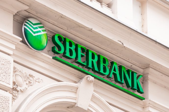 Die Außenseite eines Gebäudes in Russland mit einem grünen Sberbank-Logo und einem Schild über dem Eingang.