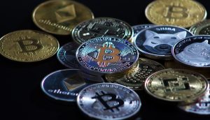Auf einer dunklen Oberfläche wird ein Stapel verschiedener physischer Kryptowährungsmünzen angezeigt, darunter Bitcoin, Ethereum, Litecoin und andere – ein automatisch gespeicherter Entwurf der digitalen Währungswelt in greifbarer Form.