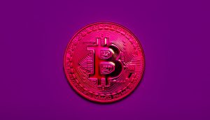 Eine metallisch glänzende Bitcoin-Münze mit geprägten Details wird vor einem einfarbig violetten Hintergrund angezeigt, wodurch das ikonische Währungssymbol hervorgehoben wird.