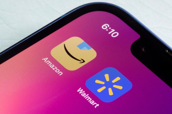 Nahaufnahme eines Smartphone-Bildschirms mit den App-Symbolen von Amazon und Walmart auf rosa Hintergrund und der Uhrzeit 6:10. Dies verdeutlicht, wie digitale Giganten wie Amazon und Walmart die Einführung von Stablecoins beeinflussen könnten.