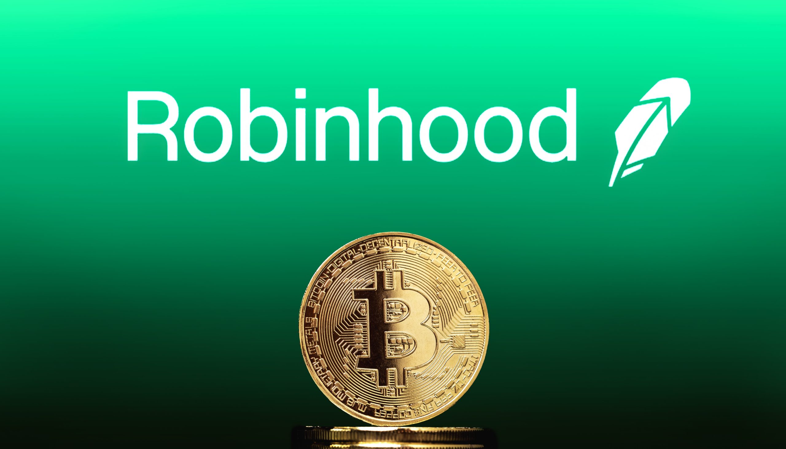 Eine goldene Bitcoin-Münze steht aufrecht vor dem Robinhood-Logo und dem Federsymbol auf grünem Hintergrund und unterstreicht das wachsende Interesse am Handel mit Bitcoin und Micro Futures.