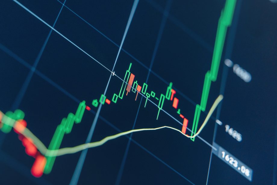 Ein digitales Aktienchart zeigt auf dunklem Hintergrund Kerzenmuster, eine gleitende Durchschnittslinie und eine starke Aufwärtsbewegung des Kurses, die von einer starken Basis ausbricht.