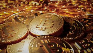 Eine Nahaufnahme mehrerer physischer Münzen mit dem Bitcoin-Symbol, das für Kryptowährung steht, die auf einem Stapel gestapelt sind – und eine der wichtigsten Erfindungen seit traditionellen Banken wie der Bank of America zeigt.