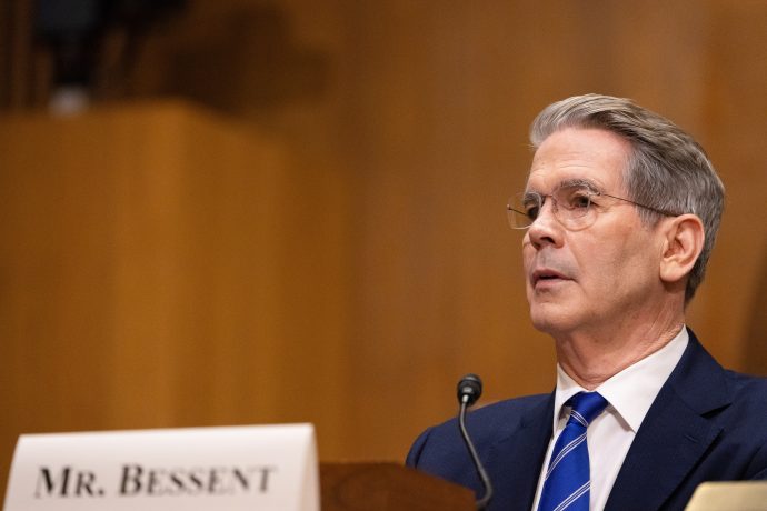A man in a suit and tie speaking into a microphone.