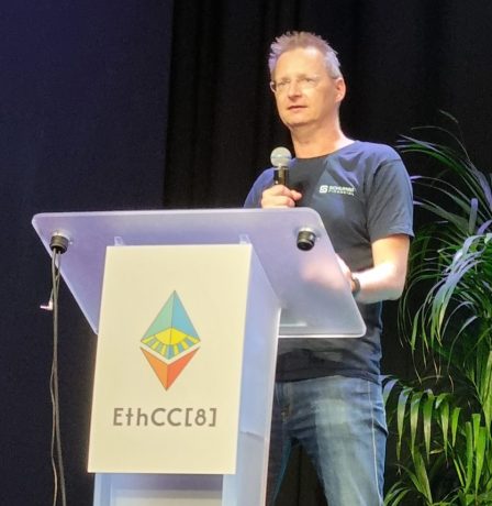 Martin Bruncko steht an einem Podium mit der Aufschrift EthCC[6] und hält einen Vortrag über Ethereum, mit einem Mikrofon, Pflanzen und einem Bildschirm im Hintergrund.