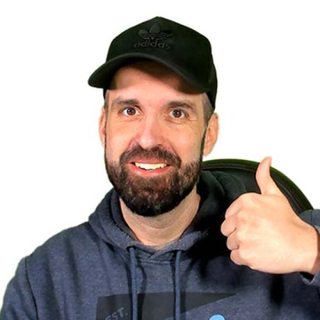 Ein Mann mit Bart, der eine schwarze Adidas-Kappe und einen grauen Kapuzenpulli trägt, streckt den Daumen nach oben und lächelt in die Kamera, um seinen 2025 Influencer Award vor einem weißen Hintergrund zu feiern.
