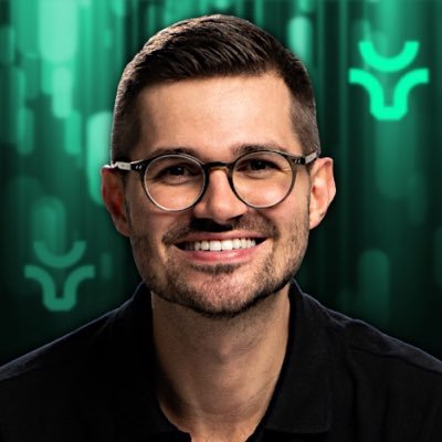 Ein Mann mit kurzen dunklen Haaren, Brille und Bart lächelt vor einem grünen, abstrakten Hintergrund mit geometrischen Formen in die Kamera, um seinen Influencer Award 2025 zu feiern.
