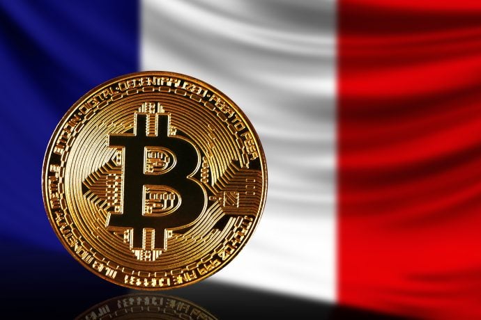 Eine goldene Bitcoin-Münze, die die Macht des Bitcoin-Minings symbolisiert, wird vor der französischen Flagge gezeigt.