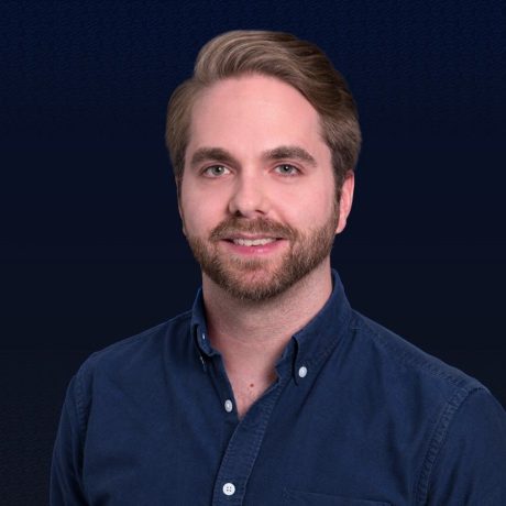 Ein Mann mit hellbraunem Haar und Bart, der ein marineblaues Button-up-Hemd trägt, lächelt vor einem dunkelblauen Hintergrund in die Kamera und feiert seinen Erfolg beim Influencer Award 2025.