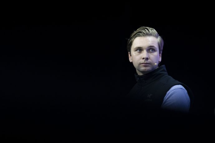 Bitvavo-Gründer Mark Nuvelstijn mit einem Mikrofon-Headset und einer dunklen Weste, der an einen Bitvavo-Analysten erinnert, blickt vor einem schwarzen Hintergrund zur Seite.