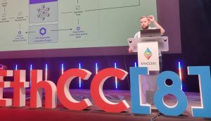 Chainlink-Gründer Sergey Nazarov präsentiert auf der EthCC[8]-Konferenz auf einer Bühne mit großen dekorativen Veranstaltungsbuchstaben und farbenfroher Beleuchtung ein technisches Diagramm zu Fonds-Tokenisierung, Chainlink-Integration und Cross-Chain-Compliance.