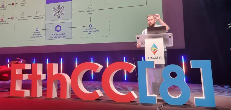 Chainlink-Gründer Sergey Nazarov präsentiert auf der EthCC[8]-Konferenz auf einer Bühne mit großen dekorativen Veranstaltungsbuchstaben und farbenfroher Beleuchtung ein technisches Diagramm zu Fonds-Tokenisierung, Chainlink-Integration und Cross-Chain-Compliance.