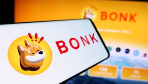 Ein Smartphone und ein Computerbildschirm zeigen das BONK-Logo - einen Cartoon-Shiba-Inu-Hund - vor einem gelben Hintergrund und heben den beliebten Solana-Memcoin hervor.