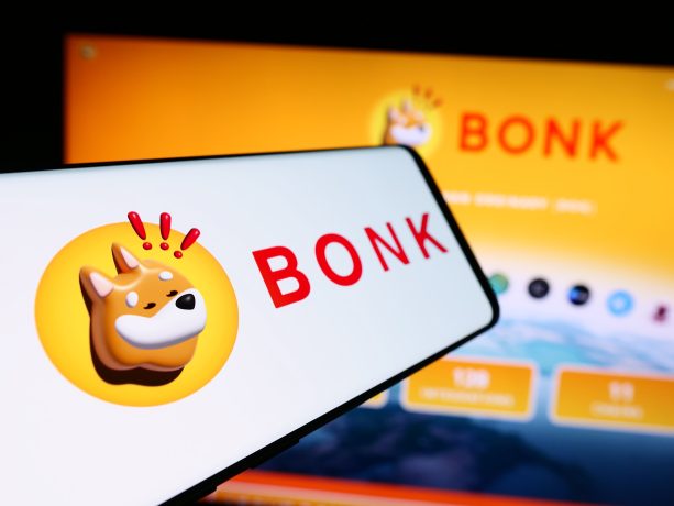 Ein Smartphone und ein Computerbildschirm zeigen das BONK-Logo - einen Cartoon-Shiba-Inu-Hund - vor einem gelben Hintergrund und heben den beliebten Solana-Memcoin hervor.