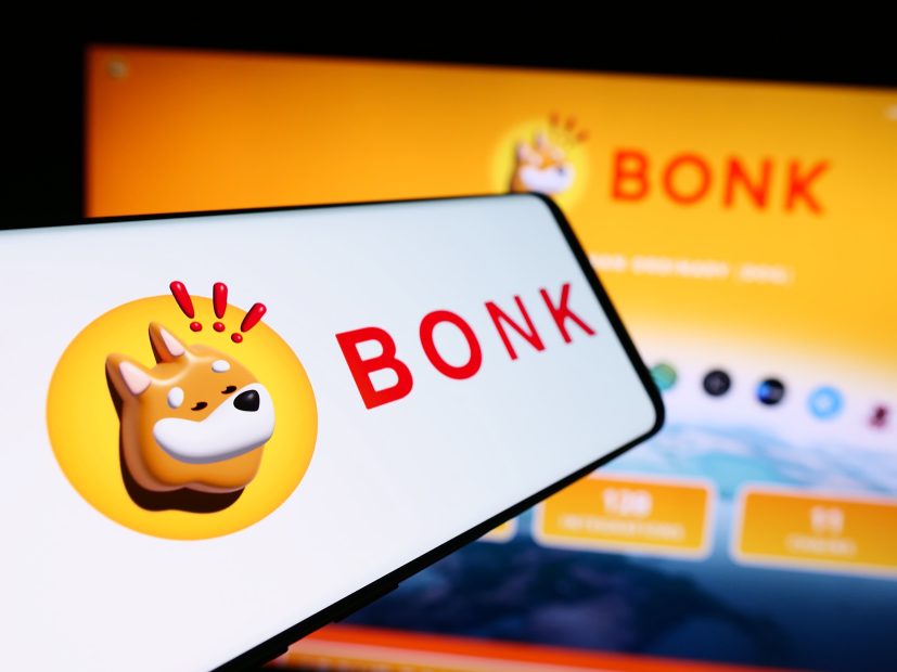Ein Smartphone und ein Computerbildschirm zeigen das BONK-Logo - einen Cartoon-Shiba-Inu-Hund - vor einem gelben Hintergrund und heben den beliebten Solana-Memcoin hervor.