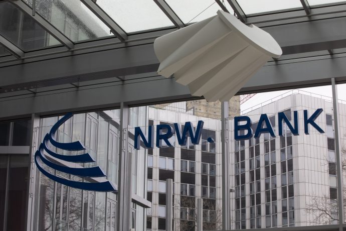 Gläsernes Bürogebäude mit NRW.BANK"-Schriftzug und blauem Logo, von innen gesehen; modernes, spiegelndes Äußeres durch die Fenster sichtbar - eine passende Kulisse für die innovative Blockchain-Anleihe der NRW.BANK.