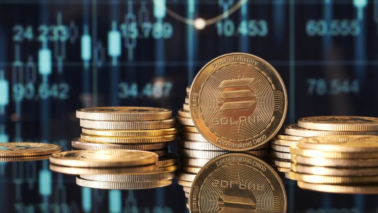 Stapel von Goldmünzen mit dem Solana-Logo werden vor einem digitalen Chart mit Solana-Finanzdaten und Candlestick-Grafiken angezeigt.