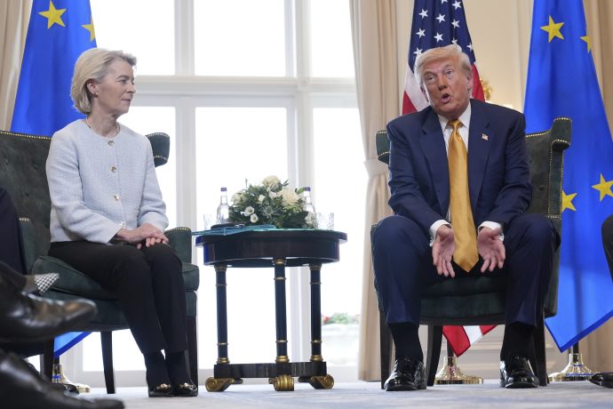 Ursula von der Leyen und Donald Trump sitzen auf Stühlen mit einem kleinen Tisch zwischen ihnen, vor EU- und US-Flaggen, in einer formellen Diskussion - vielleicht über USD-Stablecoins als Bedrohung für die Finanzstabilität.