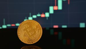 Eine physische Bitcoin-Münze steht vor einem unscharfen digitalen Candlestick-Diagramm, das die Kursentwicklung von Kryptowährungen zeigt und die Überschneidung von traditionellen Anlagen wie Almonty Industries und digitalen Vermögenswerten hervorhebt.