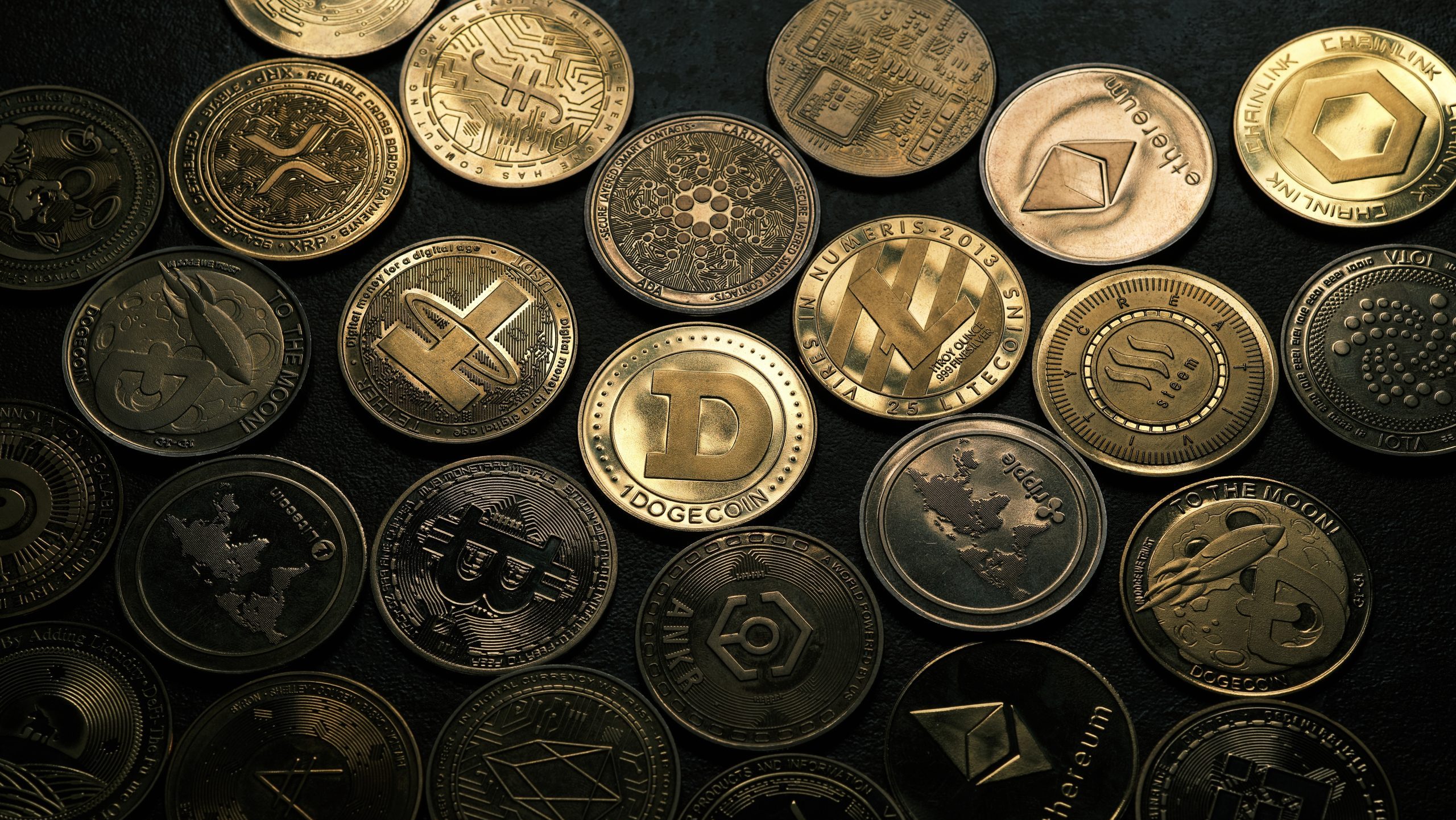 Verschiedene physische Münzen mit verschiedenen Kryptowährungslogos, darunter Bitcoin, Ethereum, Dogecoin und andere, sind in Reihen auf einer dunklen Oberfläche angeordnet und fangen den vielfältigen Geist von Altseason ein.