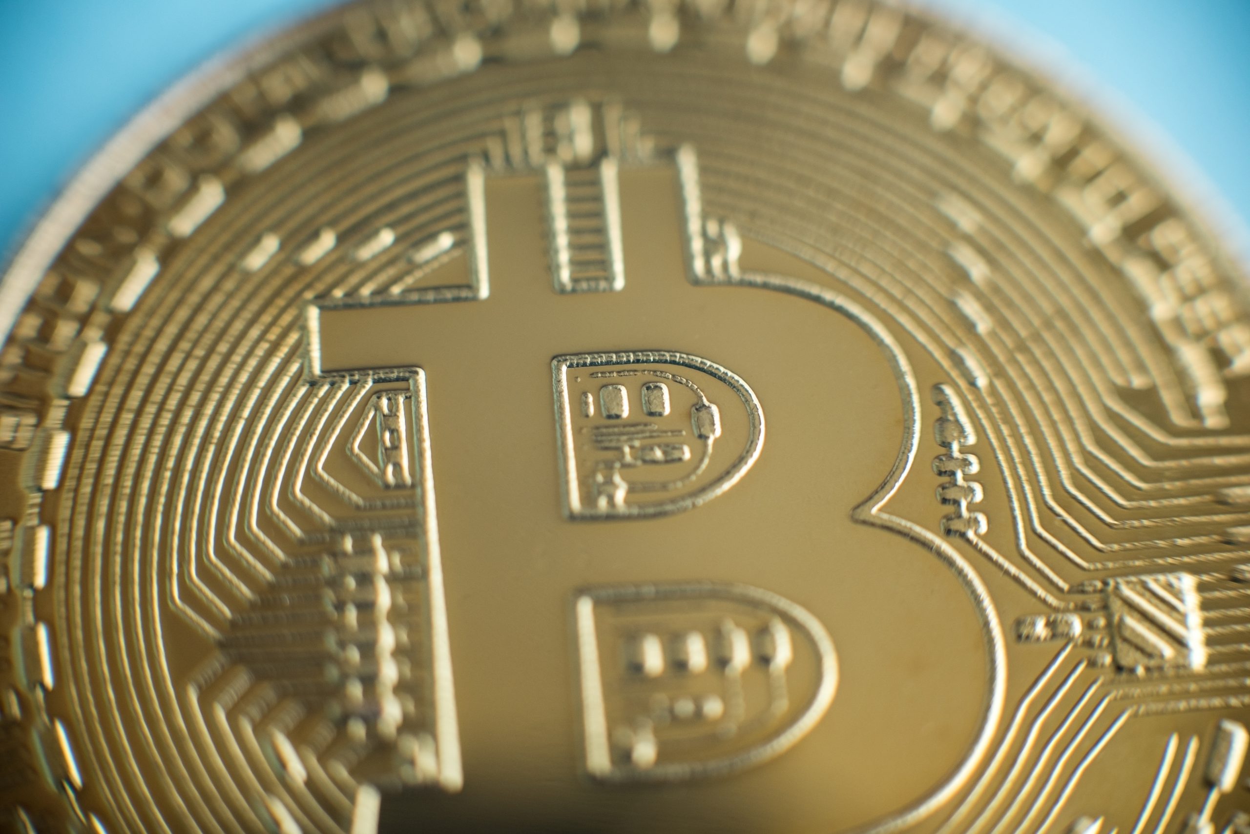 Nahaufnahme einer goldfarbenen physischen Münze mit dem Bitcoin-Logo, digitalen Schaltkreisen und einer Anspielung auf die Welt der Kryptowährungen.