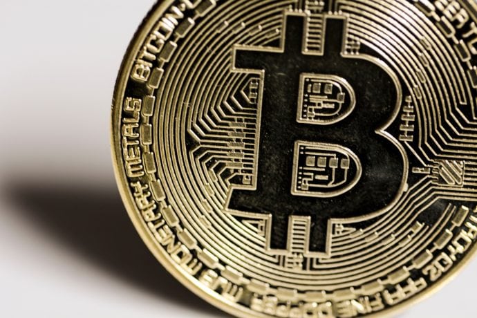 Nahaufnahme einer physischen Bitcoin-Münze mit dem ikonischen Bitcoin-Symbol, kreislaufähnlichen Mustern und den Worten BITCOIN und MONETARY METALS am Rand.