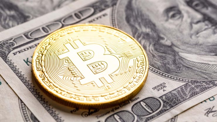 Eine goldfarbene Bitcoin-Münze ruht auf mehreren Hundert-Dollar-Scheinen und symbolisiert den wachsenden Einfluss von Bitcoin im modernen Finanzwesen.