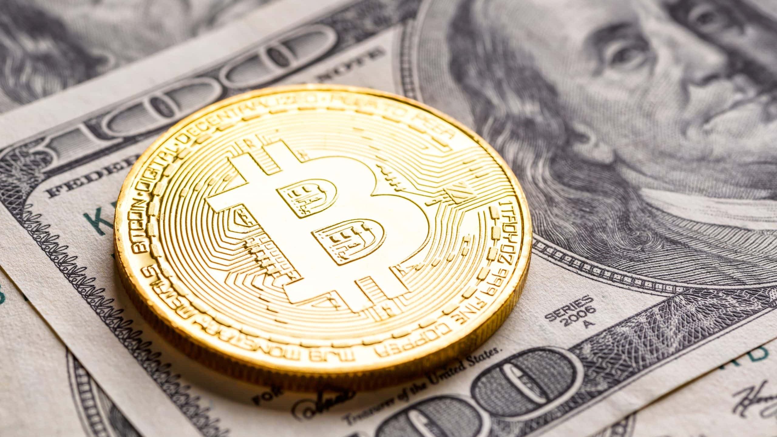 Eine goldfarbene Bitcoin-Münze ruht auf mehreren Hundert-Dollar-Scheinen und symbolisiert den wachsenden Einfluss von Bitcoin im modernen Finanzwesen.