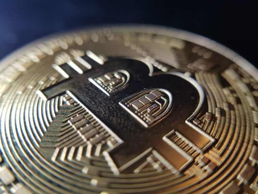 Nahaufnahme einer physischen Bitcoin-Münze mit dem eingravierten Symbol und einem detaillierten Schaltkreisdesign auf der goldfarbenen Oberfläche.