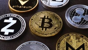 Eine Nahaufnahme verschiedener physischer Kryptowährungsmünzen, darunter Bitcoin, Ethereum und XRP, die auf einer dunklen Oberfläche angeordnet sind.