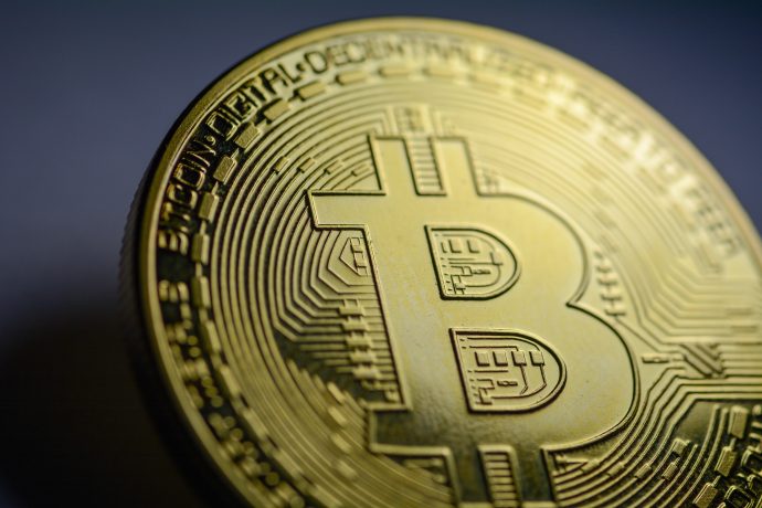 Nahaufnahme einer goldfarbenen Bitcoin-Münze mit dem Bitcoin-Logo und kreislaufähnlichen Musterdetails, die symbolisieren, dass auch Kleinanleger an der Welt der Kryptowährung teilhaben können.