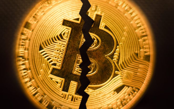 Eine goldfarbene Bitcoin-Münze mit einem fetten, gezackten Riss, der vertikal durch die Mitte verläuft und eine Teilung oder Unterbrechung innerhalb der Bitcoin-Kryptowährung symbolisiert.