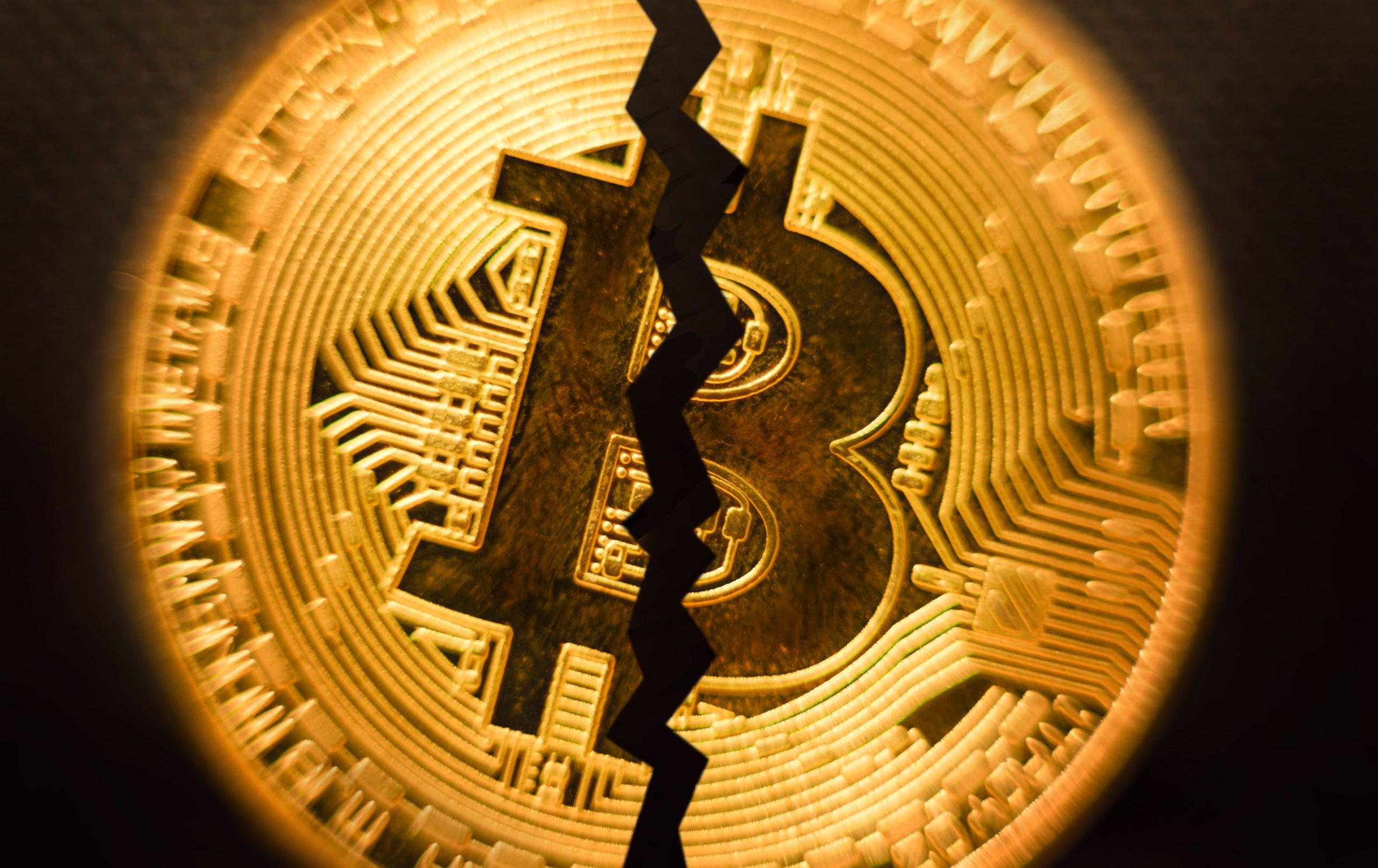 Eine goldfarbene Bitcoin-Münze mit einem fetten, gezackten Riss, der vertikal durch die Mitte verläuft und eine Teilung oder Unterbrechung innerhalb der Bitcoin-Kryptowährung symbolisiert.
