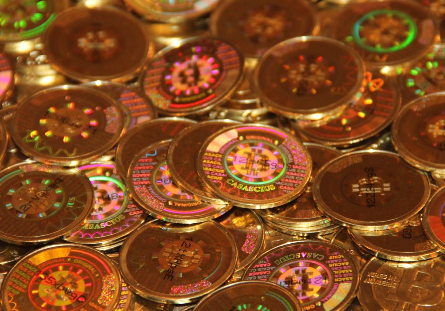 btcpile2-1200 Ein Stapel physischer Casascius-Gold-Barren-Bitcoins mit reflektierenden Hologramm-Aufklebern, die die Details der digitalen Währung anzeigen und auf der Oberfläche mit 100 BTC markiert sind.
