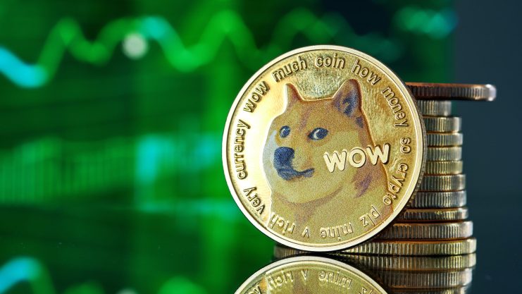 Ein Dogecoin-Token mit dem ikonischen Shiba-Inu-Hund steht auf gestapelten Münzen, während im Hintergrund eine grüne, schwankende Dogecoin-Grafik verschwommen dargestellt ist.