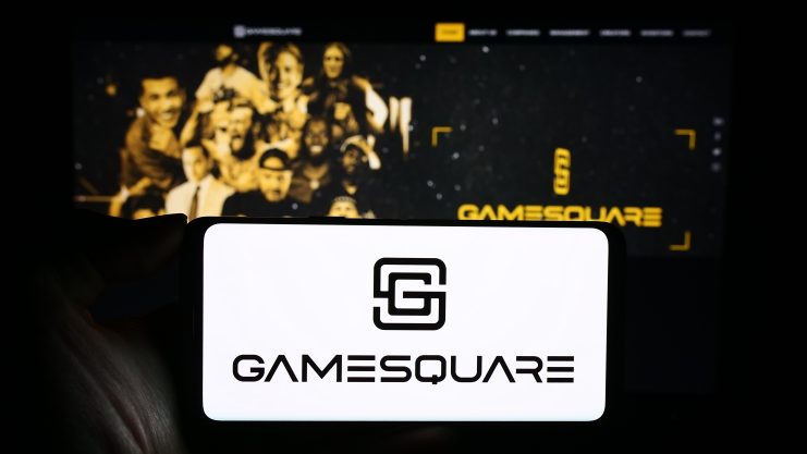 Eine Person hält ein Smartphone mit dem GameSquare-Logo vor einem Computerbildschirm, der die GameSquare-Website zeigt und die Integration mit Ethereum hervorhebt.