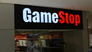 Das Äußere einer GameStop-Filiale mit einem schwarzen Schild, auf dem der Name des Geschäfts in weißer und roter Schrift über dem Eingang zu lesen ist, spiegelt die Präsenz von GameStop inmitten von Diskussionen über Bitcoin und Inflationsschutz wider.