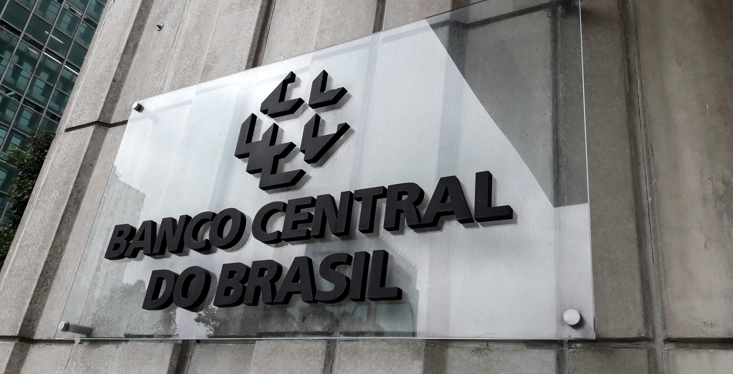 Ein Schild an einer Betonmauer mit der Aufschrift Banco Central do Brasil und einem geometrischen Logo über dem Text weist auf diese wichtige Institution hin, die häufig in Diskussionen über finanzielle Sicherheit und Hackerschutz erwähnt wird.