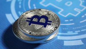 Zwei silberne physische Münzen mit dem Bitcoin-Symbol ruhen auf einer blauen Oberfläche mit einem großen, stilisierten Bitcoin-Logo, das den Einfluss der digitalen Währung und kreislaufähnliche Designelemente hervorhebt.