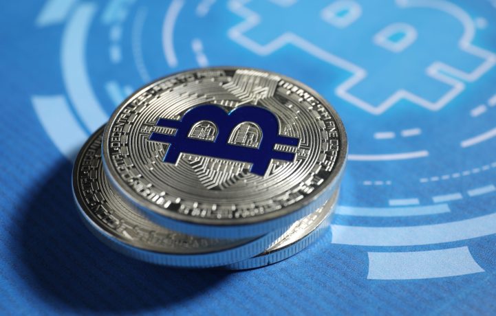 Zwei silberne physische Münzen mit dem Bitcoin-Symbol ruhen auf einer blauen Oberfläche mit einem großen, stilisierten Bitcoin-Logo, das den Einfluss der digitalen Währung und kreislaufähnliche Designelemente hervorhebt.
