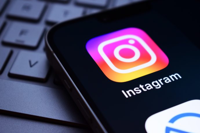 Ein Smartphone-Bildschirm mit dem Instagram-App-Symbol, auf dem das Zora-Logo zu sehen ist, auf einer Laptop-Tastatur.