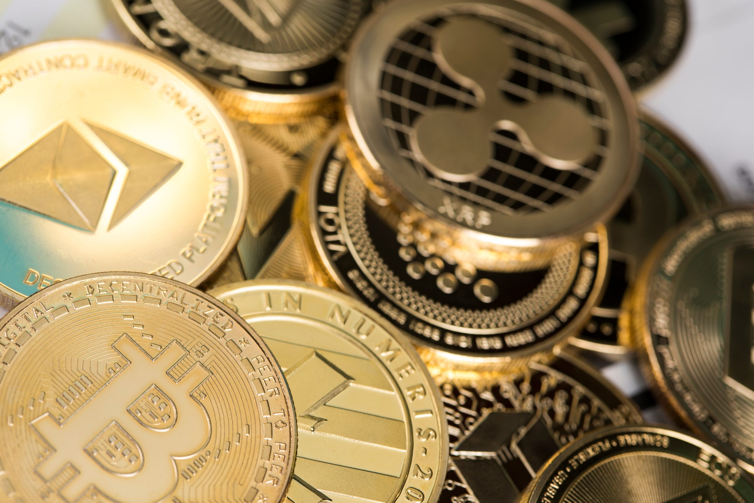 Eine Nahaufnahme von verschiedenen physischen Münzen mit Krypto-Logos, darunter Bitcoin, Ethereum und Ripple.
