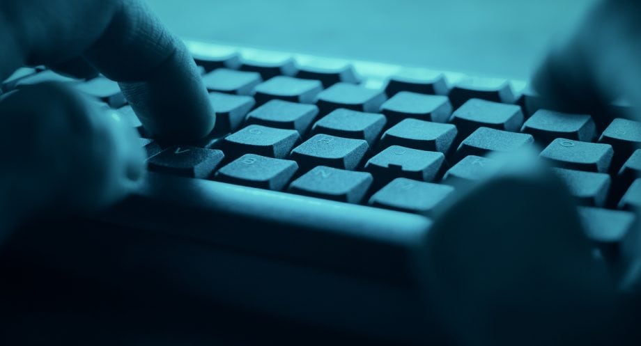 Nahaufnahme von Händen, die auf einer Computertastatur in einem blauen Farbton tippen, der an die schnelllebige Welt von Krypto erinnert.
