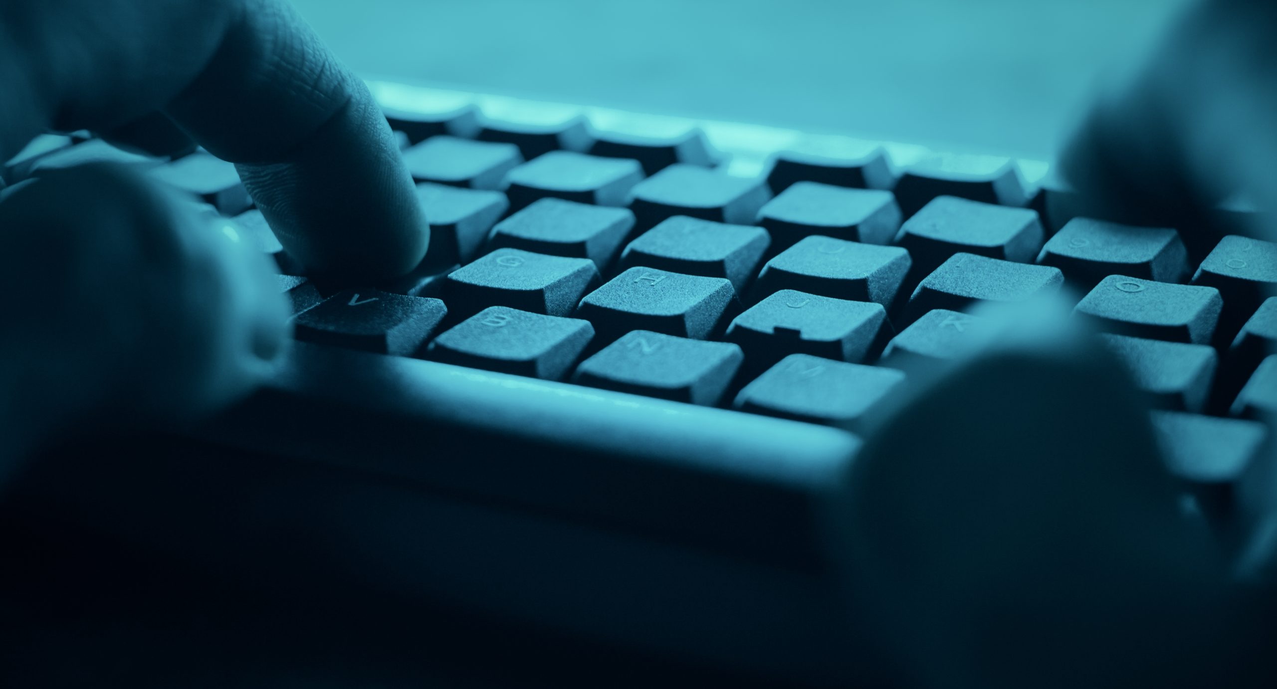 Nahaufnahme von Händen, die auf einer Computertastatur in einem blauen Farbton tippen, der an die schnelllebige Welt von Krypto erinnert.
