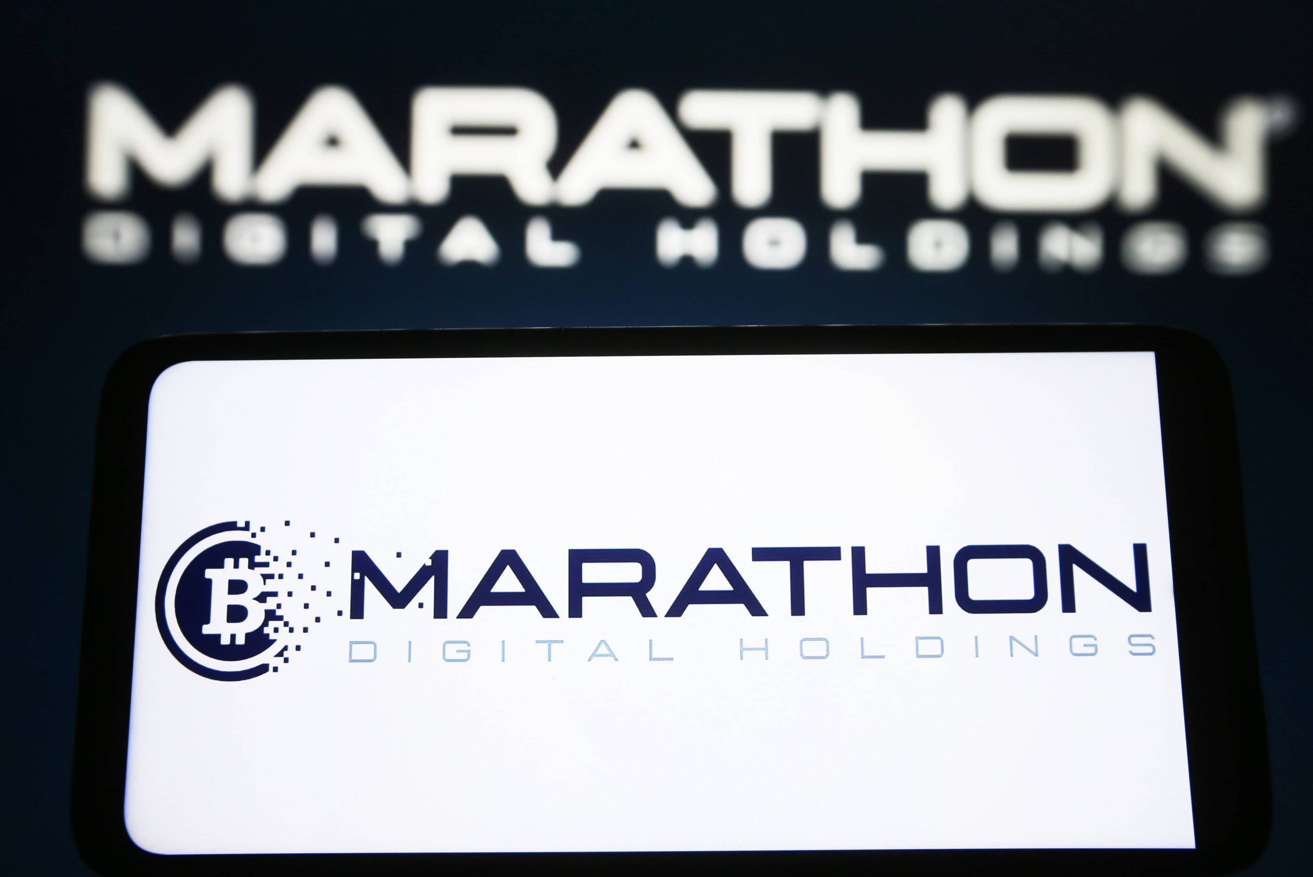 Auf einem Bildschirm wird das Logo von MARA Marathon Digital Holdings angezeigt, mit einem verschwommenen Firmennamen im Hintergrund.