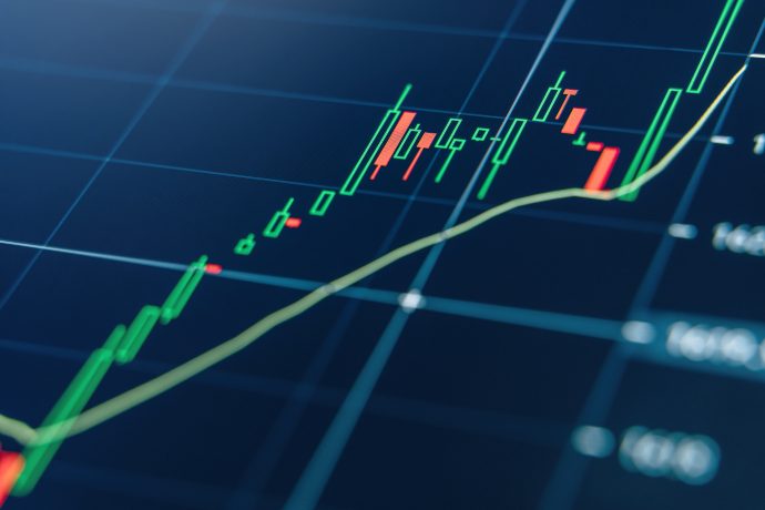 Ein digitaler Bildschirm zeigt einen Candlestick-Chart mit grünen und roten Balken, einer gelben Trendlinie und einem dunklen Gitterhintergrund, der die Finanzmarktaktivitäten und die Auswirkungen der Tokenisierung hervorhebt.