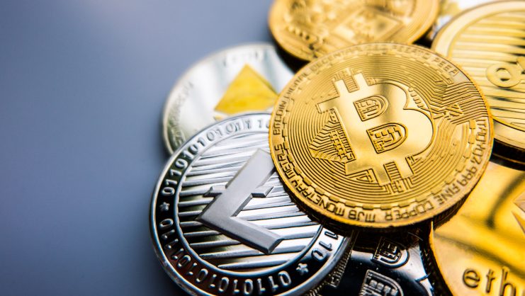 Eine Nahaufnahme verschiedener Kryptowährungsmünzen, darunter Bitcoin, Litecoin und Ethereum, die auf einem neutralen Hintergrund gestapelt sind - Symbole für digitale Vermögenswerte, die passives Einkommen bieten können.