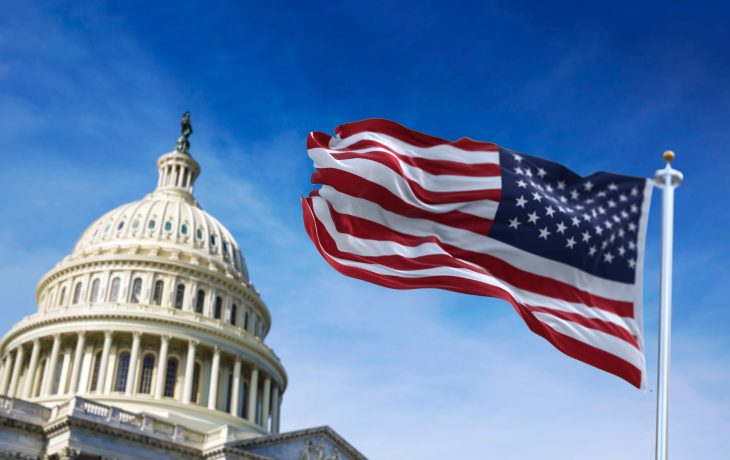 Die Kuppel des Kapitols der Vereinigten Staaten mit einer wehenden amerikanischen Flagge im Vordergrund vor einem blauen Himmel, die den dynamischen Aufstieg von Krypto und die Aufregung der Altcoin-Saison symbolisiert.