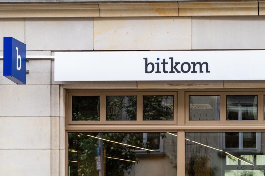 Über den Fenstern eines Gebäudes ist ein Schild mit der Aufschrift bitkom angebracht, links davon ein blaues Schild mit einem kleinen b - ein Zeichen dafür, dass sich deutsche Unternehmen auf Trends wie Bitcoin und digitale Zahlungen einstellen.